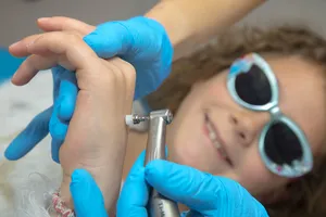 Une petite fille souriante, portant des lunettes de protection, pendant un soin