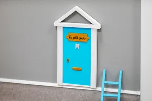 La petite porte bleue de la souris, avec son échelle, fixée en bas d’un mur du cabinet