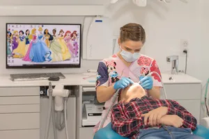 Un enfant soigné au fauteuil pendant qu’un écran diffuse un dessin animé