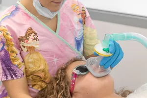 Une enfant reçoit du MEOPA par masque nasal, accompagnée par la praticienne